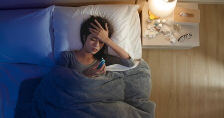 Overhead View of asian woman get sick and has a fever while lying on the bedの写真素材