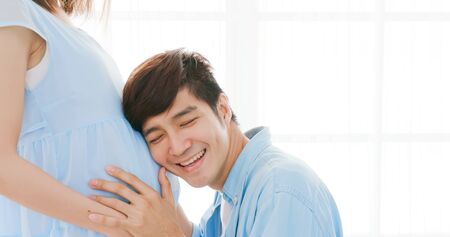 happy pregnant couple expecting baby and listen to babyの写真素材