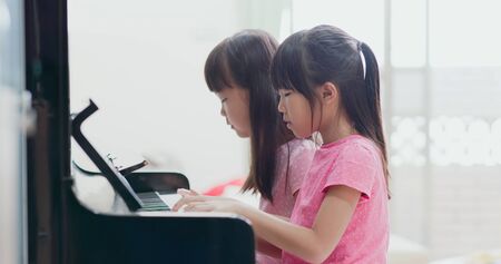 Two asian girls play pianoo elegantly at homeの写真素材