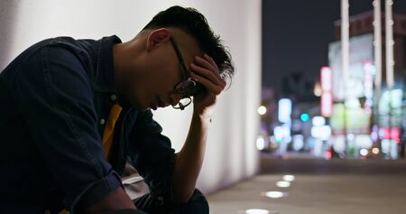 asian man is upset about something and sit outdoor in the eveningの写真素材
