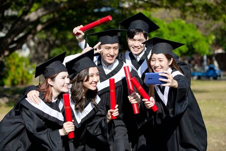 group happy graduates students use mobile phone to take selfie togetherの写真素材