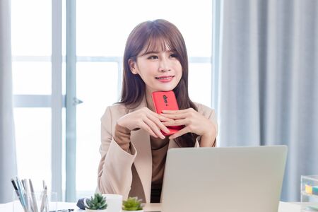 woman use phone and computer work at home - she is thinking somethingの写真素材