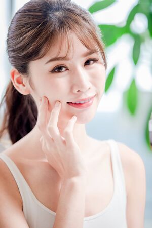 close up of young asian skin care girl touch her face and look to you with smileの写真素材