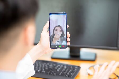 Telemedicine concept - asian female patient consult her health condition to male doctor by talking on mobile phone and she have a sneezeの写真素材