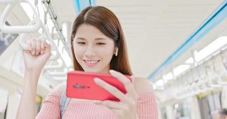 asian woman use wireless earbuds to listen music by 5g smartphone in the metro-location taipei and taiwanの写真素材