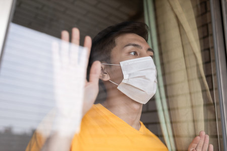 asian young man with face mask stay isolation at home for self quarantine due to an epidemic of...