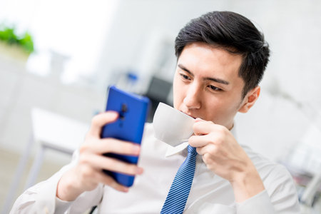 asian young man is sitting on the sofa and using laptop leisurely at home