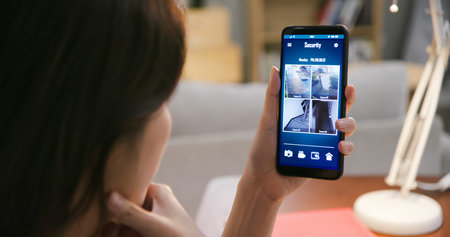 close up of asian woman rear view using home security camera system on smart phone