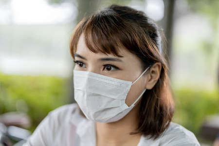 Asian businesswoman wear face mask and use laptop to work with bicycle in the parkの写真素材