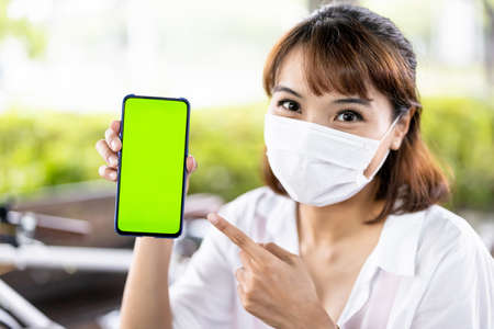 Asian businesswoman wear face mask and use laptop to work with bicycle in the parkの写真素材