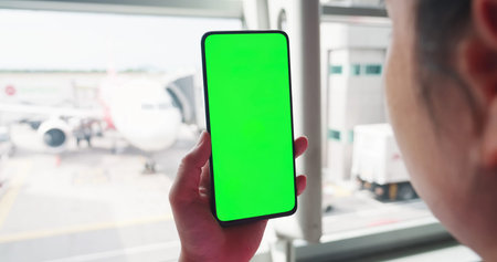 asian woman holding green screen smart phone in airport