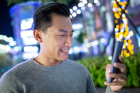 asian man use smart phone outdoor in the eveningの写真素材