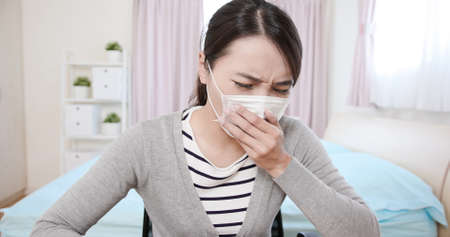 Telemedicine concept-asian female patient consult her health condition to doctor by talking on mobile phone and she has feverの写真素材