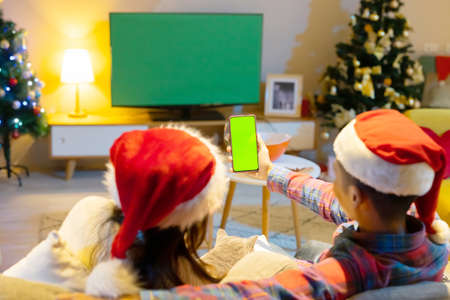 asian young man is playing and winning motion sensing game on a green chroma key TV screen and shake his arm at homeの写真素材