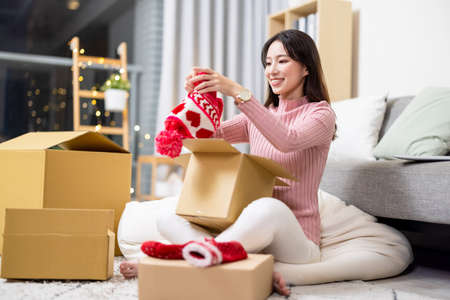 Asian woman unpacking winter hat at homeの写真素材