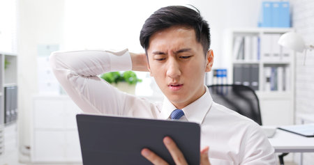 asian young businessman wearing face mask has headache or feel depress in office and his colleague...