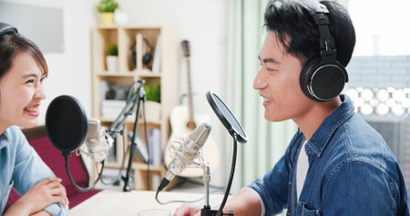 asian woman and man with microphone are recording podcast at studioの写真素材