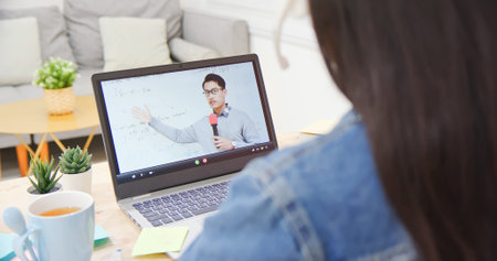rear view of asian girl is learning math online through listeing to male college teacher teaching...