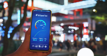 woman holds smartphone with 5g speed test near department store with crowded peopleの写真素材