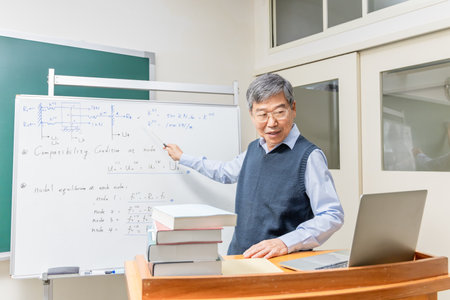 Asian mature male professor teach Engineering online through laptop in classroom at graduate schoolの写真素材