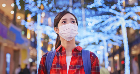 asian young female backpacker wearing face mask walking down the street in Taipei city at night during quarantine coronavirus COVID-19 pandemicの写真素材