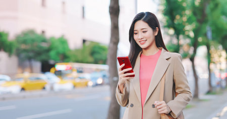 asian businesswoman use 5G smartphone outdoor while commutingの写真素材