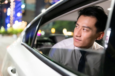 close up of asian successful businessman look outside window in the car at nightの写真素材