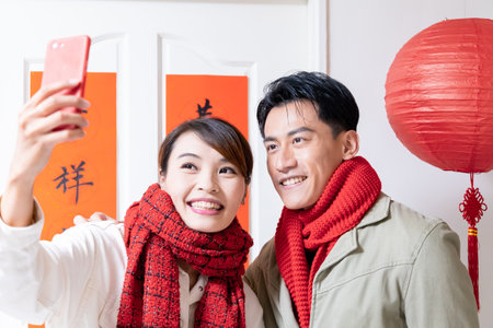 Loving asian young couple making a selfie in front of the door with spring festival coupletsの写真素材