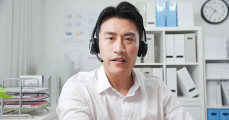 telework concept-asian businessman wears headset who has some machine mistakes about his webcam to join a video meeting in the officeの写真素材