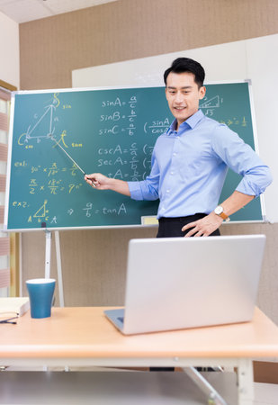asian senior high school male teacher teach math online through laptop in classroomの写真素材