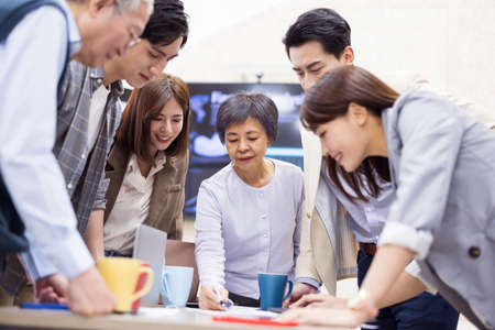 Group of businessmen standing around the table and try to generate good ideas as many as they can-senior woman leaderの写真素材
