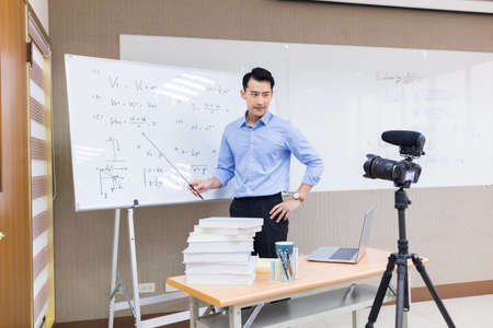 asian senior high school male teacher teach physical online through camera in classroomの写真素材