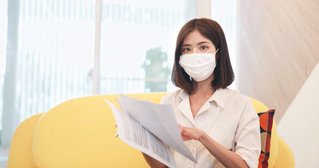 telework concept-asian business woman use webcam to join a video meeting with face mask at home
