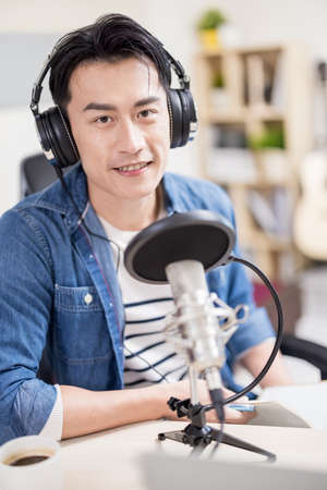 asian man with headphones and microphone recording podcast at studioの写真素材