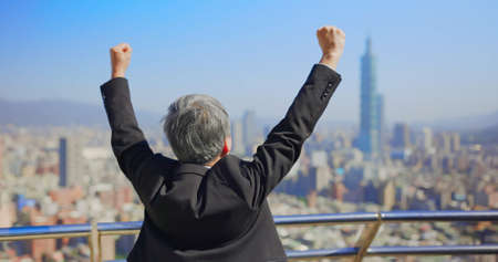 asian senior businessman raise his arm with fist gesture in cityの写真素材