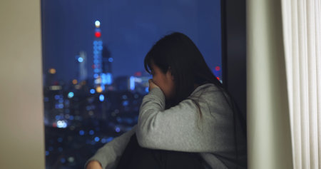 asian woman feel depressed near window at home