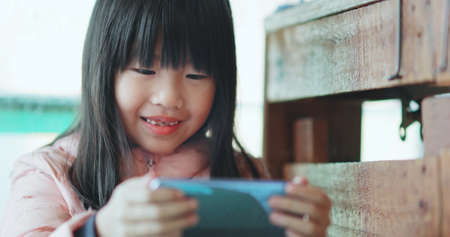 Asian girl uses cell phone to watch video and smilesの写真素材