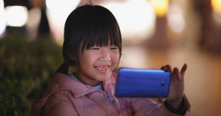 Asian girl uses cell phone to watch video and smilesの写真素材