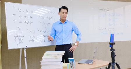asian senior high school male teacher teach physical online through mobile phone in classroom