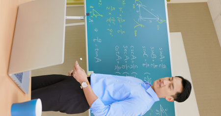 asian senior high school male teacher teach math online through laptop in classroom
