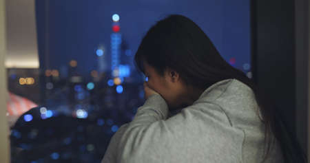 asian woman feel depressed and crying near window at homeの写真素材