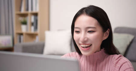 close up of asian young woman has video chat by laptop computer with friend happily in the living room at homeの写真素材