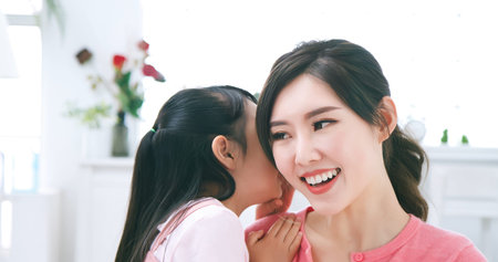 asian daughter whisper to mom and mother smile