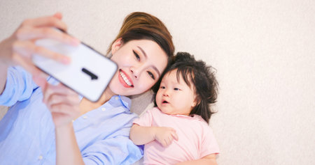 asian young mother take selfie with her daughter at home happily