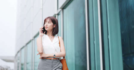 asian young businesswoman use smart phone while commuting in cityの写真素材