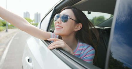 Asian pretty girl wearing sunglasses have road trip by car and look out of the window feel excitedの写真素材