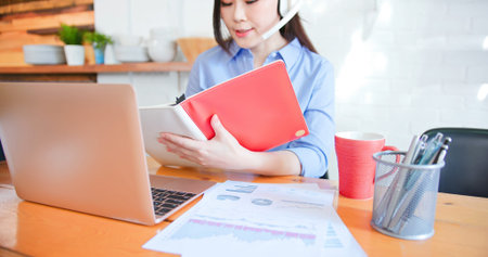 telework concept-Asian woman use computer to work and has a video meeting at home