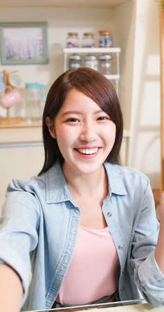 asian young woman has video chat by smartphone with friend happily at homeの写真素材