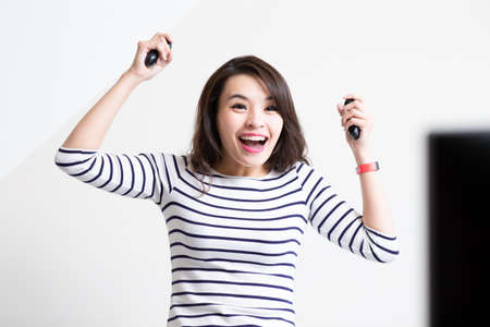 asian woman is playing motion sensing TV game and win at homeの写真素材