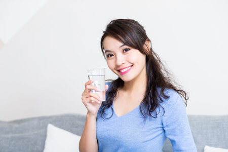 asian young woman holding a glass of water has healthy life and she smile at you